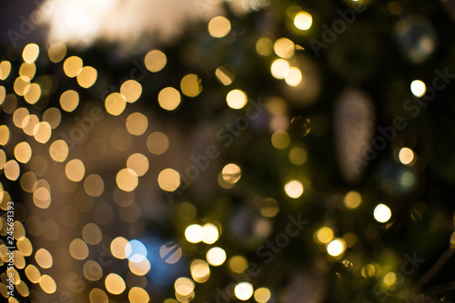 Out of focus texture background of Christmas tree with ornaments and Christmas lights.