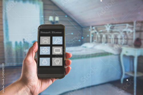 Smart home technology interface on smartphone app screen with augmented reality (AR) view of internet of things (IOT) connected objects in the apartment interior, person holding device