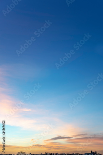 Portrait view of an early morning sky with tin and small clouds lighted by the vivid morning sunrise at the horizon