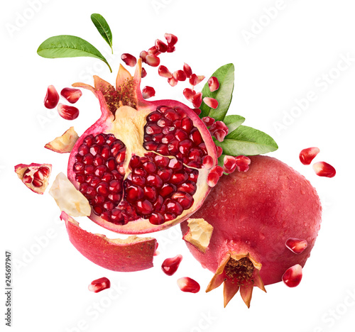 Flying in air fresh ripe whole and cut pomegranate with seeds and leaves photo