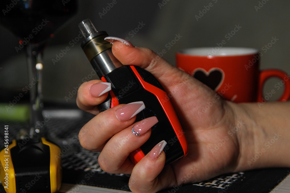 Woman's hands holding electronic cigarette. Nail art on hers nails.
