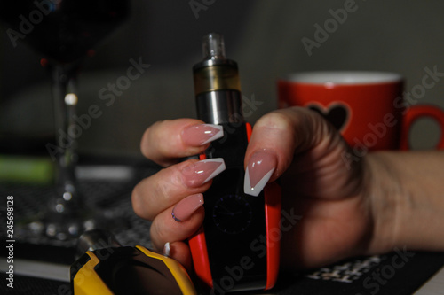 Woman's hands holding electronic cigarette. Nail art on hers nails.
