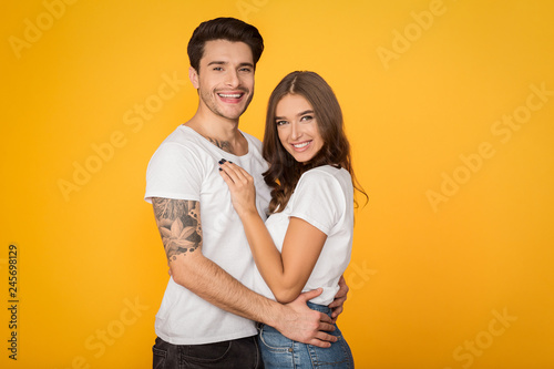 Happy loving couple embracing against yellow background © Prostock-studio