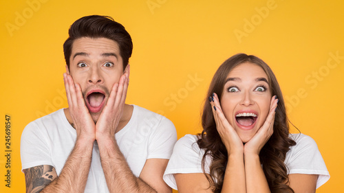 Surprised couple screaming and touching face over background