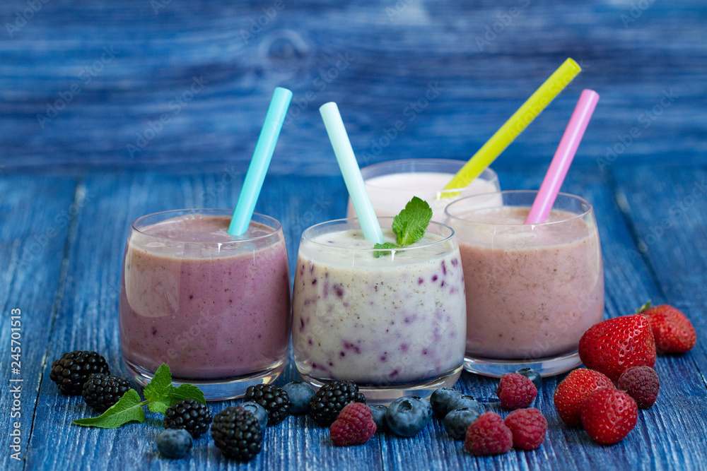 Raspberry, strawberry, blackberries, blueberry smoothie on blue wooden background. milkshake with fresh berries. healthy fruit smoothie with ingredients. well being and weight loos concept Raspberry, strawberry, blackberries, blueberry smoothie on blue wooden background. milkshake with fresh berries. healthy fruit smoothie with ingredients. well being and weight loos concept