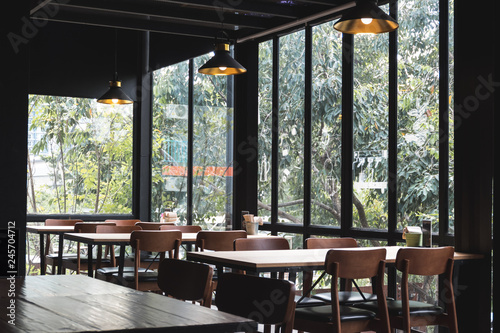 Table and chair set in modern cafe minimalistic interior design with big window and hanging ceiling lamps
