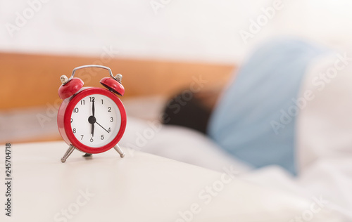 Man sleeping with alarm clock on foreground