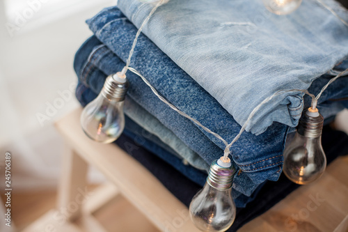 Jeans, light bulbs, denim cotton, blue. Stack of jeans in the interior. Clothing.
