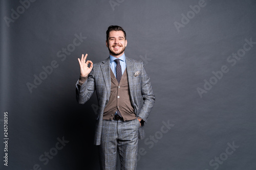 Portrait of excited satisfied cheerful confident positive handsome demonstrating thumbs-up pointing up isolated on gray background.