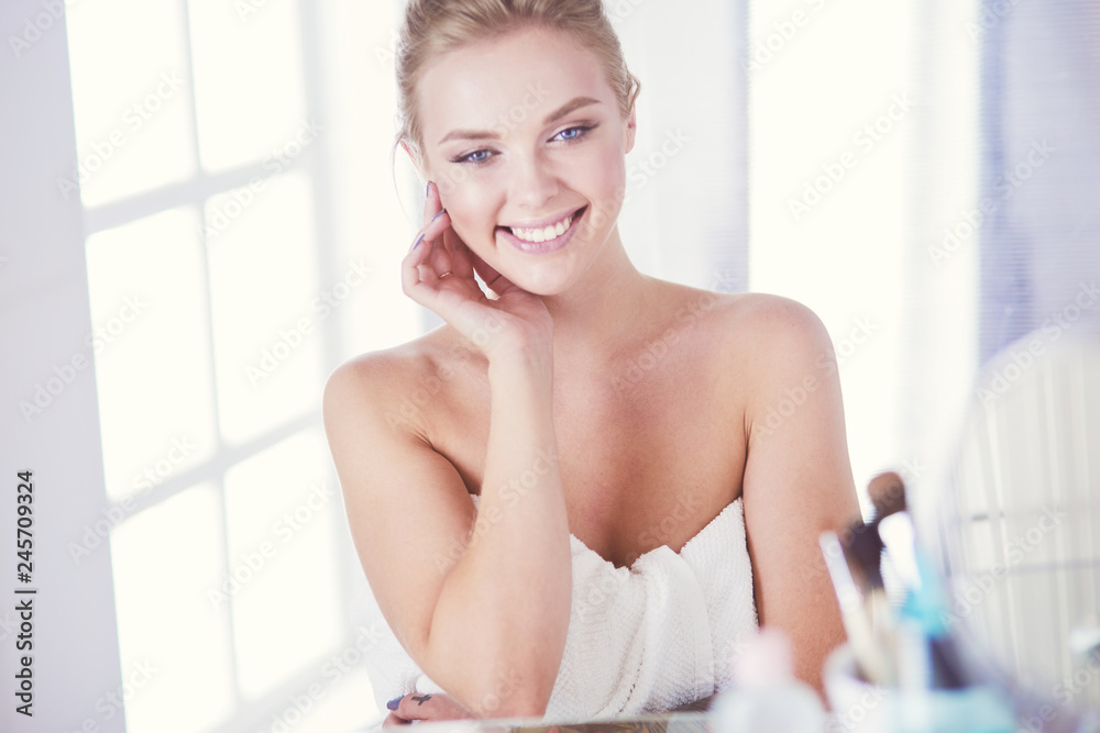 Young woman in bathrobe looking in bathroom mirror Young woman in bathrobe looking in bathroom mirror
