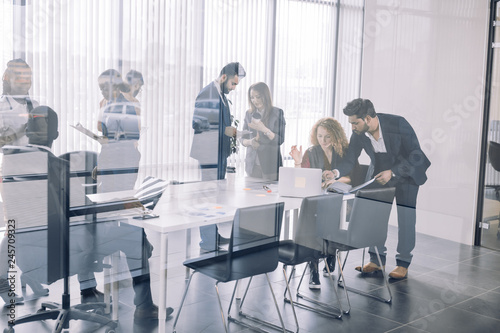 Positive multiracial diverse business people in formal and casual wear are discussing forum topics and sharing impressions while standing in conference room at break. Toned image