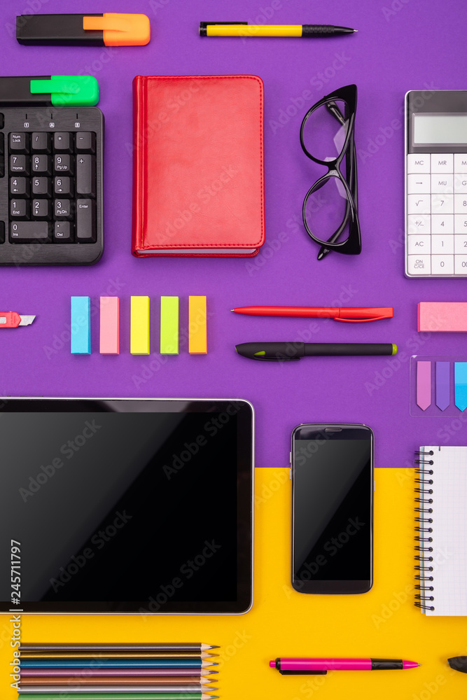 Modern working place with tablet, calculator, notebook and smartphone on purple and orange background. Business concept