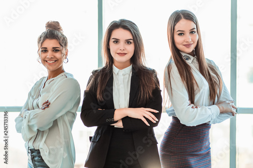 With pleasure, three business women cross their arms, looking at the camera. photo