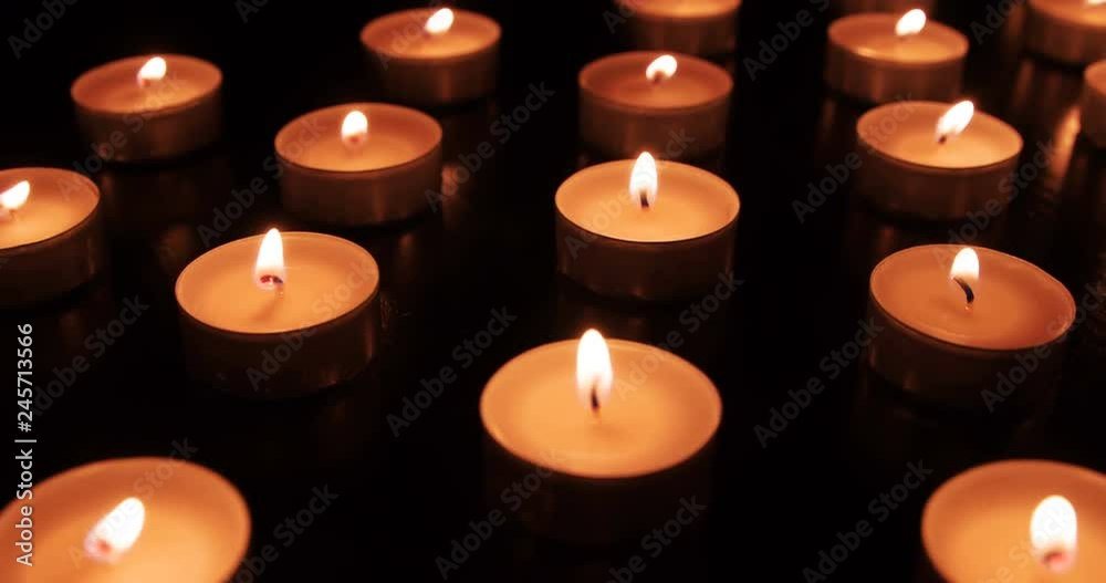 Many Burning Candles. The camera moves slowly along the field with burning small candles in total darkness. Flames moving by the movement of air Many Burning Candles. The camera moves slowly along the field with burning small candles in total darkness. Flames moving by the movement of air