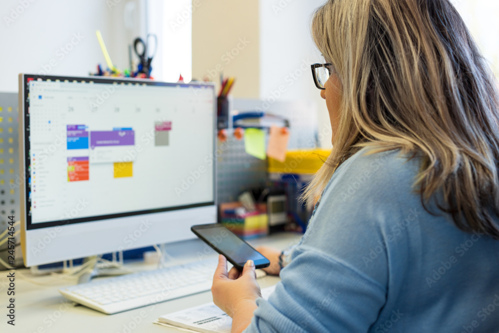 Female child therapist in an office during a phone call, using online calendar to schedule patients appointments. Calendar Planner Organization Management Concept. Female child therapist in an office during a phone call, using online calendar to schedule patients appointments. Calendar Planner Organization Management Concept.