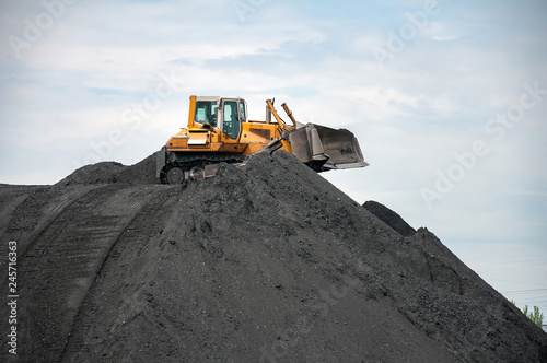 caterpillar tractor and travelling crane load black coal on supply field of thermoelectric power station