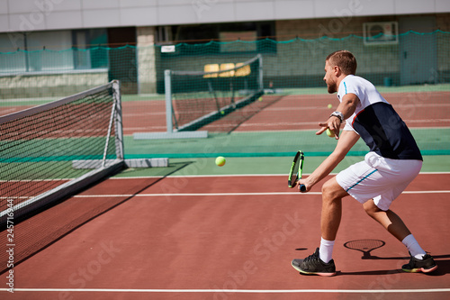 Tennis match which a serving player, keeping his eye on the ball on the outdoor training court.