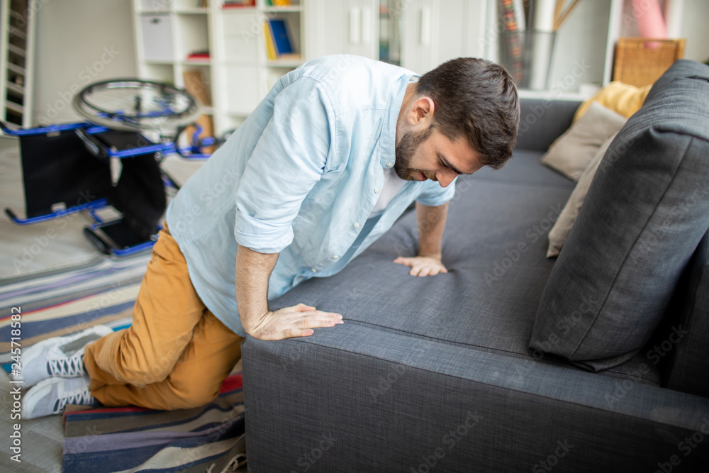 Young disable man in casualwear trying to get up on sofa from the floor  after falling off wheelchair Stock Photo | Adobe Stock
