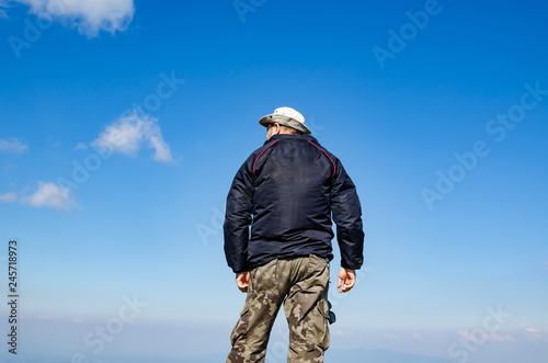 Man dressed for hiking standing against blue sky