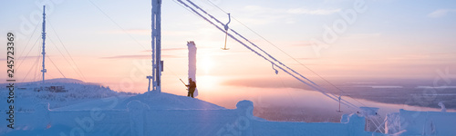 Sunny sunrise on top of the mountain in winter. Kuusamo Ruka. Finland Lapland. Snowboarder climbs the lift. Panorama view. photo