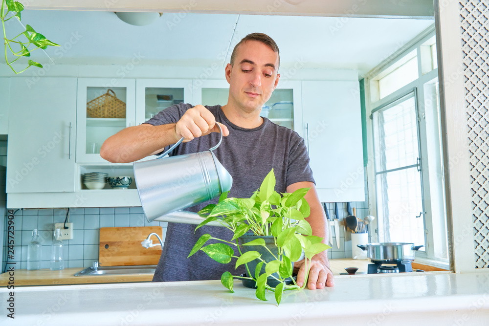 Handsome guy posing - watering plant and looking down Handsome guy posing - watering plant and looking down
