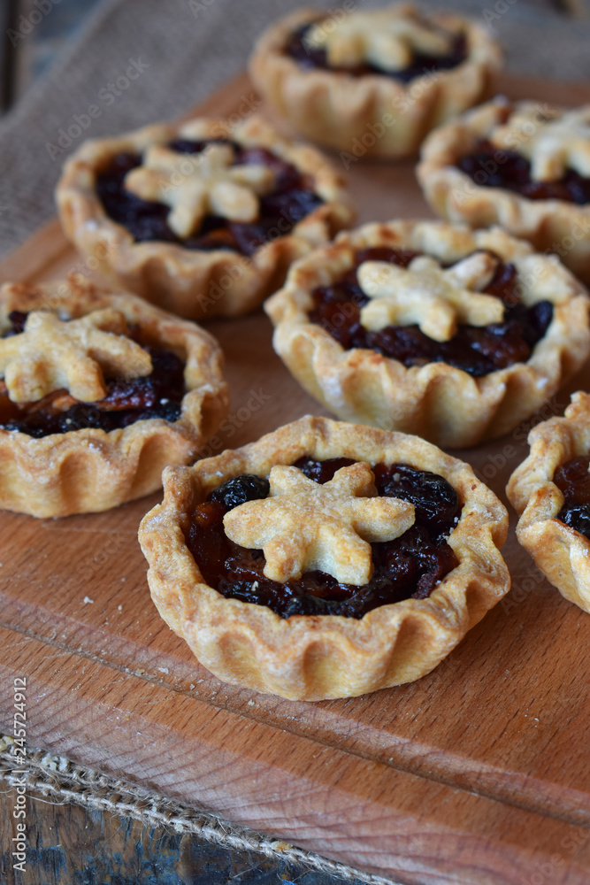 Mini Tartlets with dried fruits and nuts. Shortbread cookies with fruits stuffing on wooden background. Small sweet pie. Copy Space.