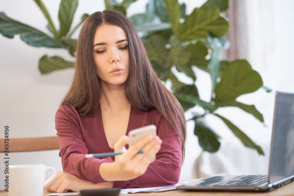 woman is distracted while working on her phone. social networks at work, effective employees in a modern office. woman is distracted while working on her phone. social networks at work, effective employees in a modern office.