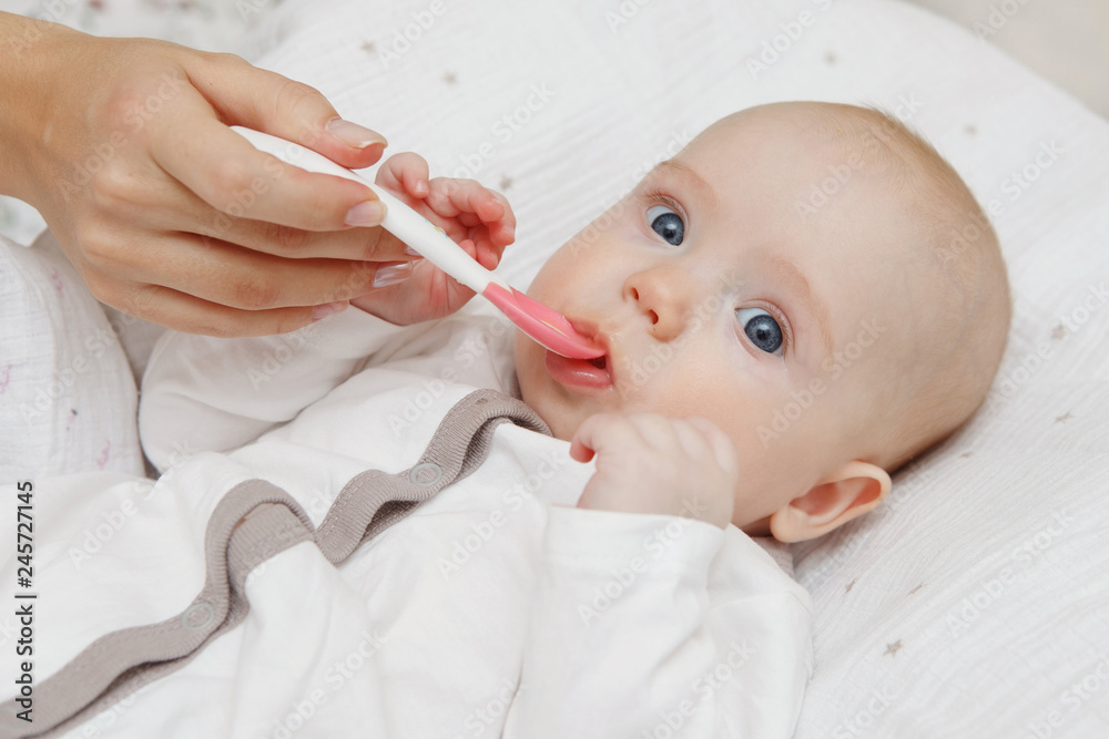 Beautiful Lovely five-month baby girl eating with a spoon. Healthy food. Maternal care. Childcare. Close-up. Beautiful Lovely five-month baby girl eating with a spoon. Healthy food. Maternal care. Childcare. Close-up.