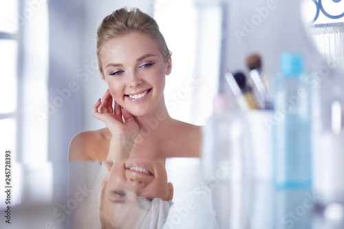 Free Download Young woman in bathrobe looking in bathroom mirror - GFXLoad