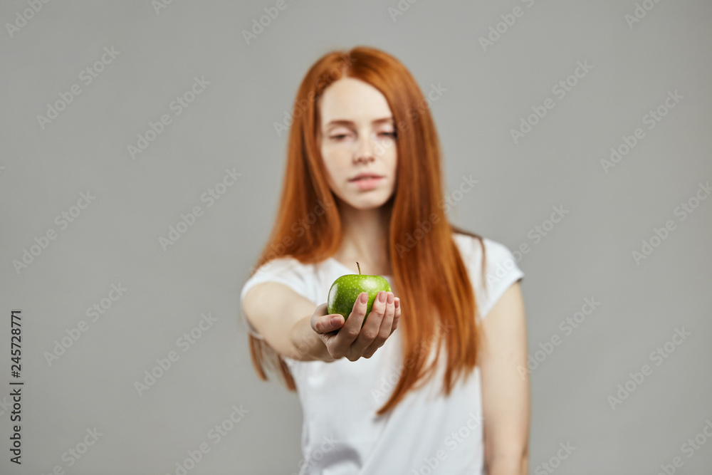 attractive girl offers a green apple. blurred image, focus on apple in hand. whuld you like an apple attractive girl offers a green apple. blurred image, focus on apple in hand. whuld you like an apple