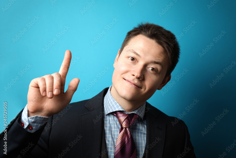 Young businessman in suit on blue background shows his hand thumbs up, symbol of success. Young businessman in suit on blue background shows his hand thumbs up, symbol of success.