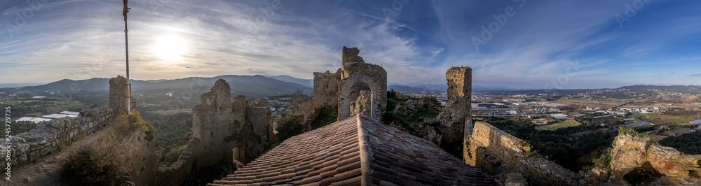 Fototapeta premium View of Palafolls castle medieval ruined stronghold between Girona and Barcelona on the Costa Brava with the Catalan flag proudly flying over the Romanesque church