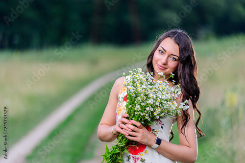 Cute smiling girl with flower wreath on the meadow at the farm. Midsummer.