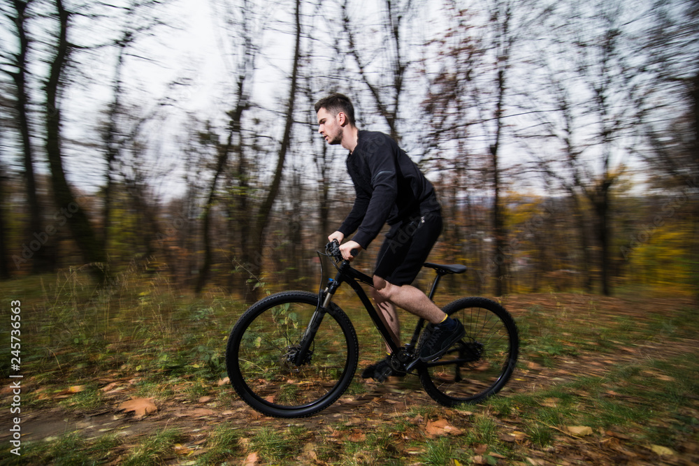 Young fit man during a bike ride on a sunny day in autumn park