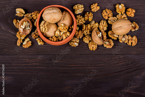 whole walnuts and kernels on wooden background, walnut on a dark old table in a clay pot