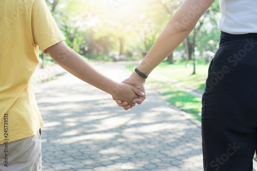 Mother with son holding hand in hand walking at the public park