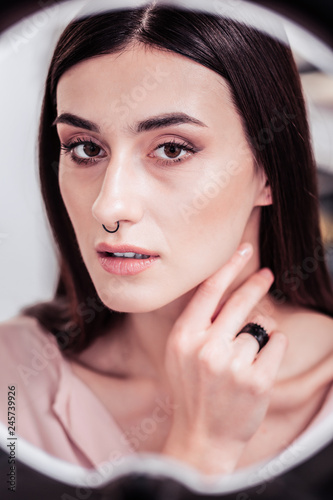 Beautiful dark haired woman looking into the mirror