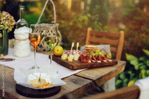 summer garden table decorated with flowers and candles  evening party with wine  cheese and fruits