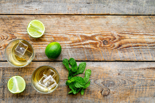 Alcoholic beverage. Whiskey with ice, mint and lime on dark wooden background top view copy space