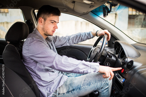 Young man finger pressing the emergency lights button while driving.