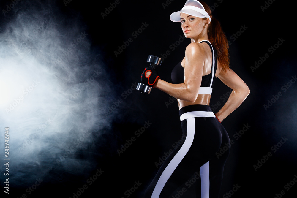 Sporty fit woman, athlete with dumbbells make fitness exercises on black background. Sporty fit woman, athlete with dumbbells make fitness exercises on black background.