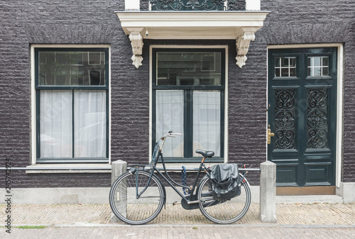 Typical Amsterdam old town street view in Netherlands with old doors and windows and vintage bicycle, front view horizontal daytime picture