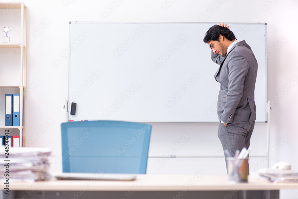 Young handsome businessman standing in front of whiteboard 