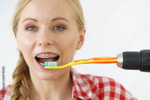 Woman burshing her teeth using drill