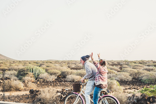 Caucasian aged mature couple have a lot of fun riding together the same bike in outdoor happy leisure activity together in relationship and forever concept - enjoy lifestyle and never end happiness