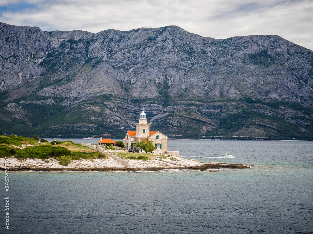 Obraz premium Ferry passing close to Sucuraj lighthouse on Hvar island, Croatia