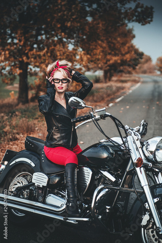 Beautiful biker woman posing outdoor with motorcycle. Pin-up style. 