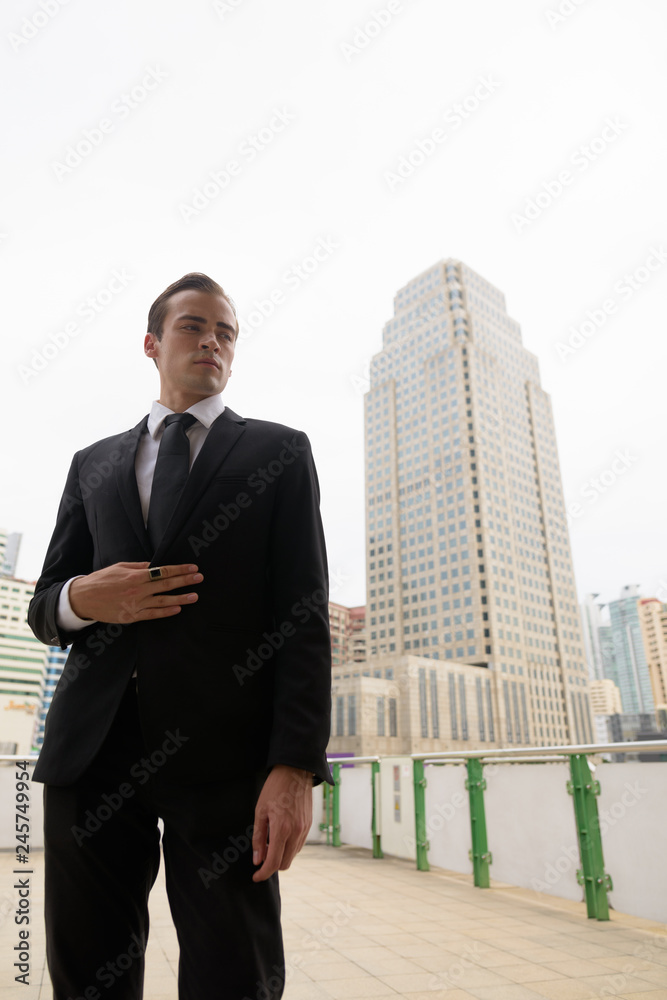 Portrait of young businessman wearing suit and standing in city Portrait of young businessman wearing suit and standing in city