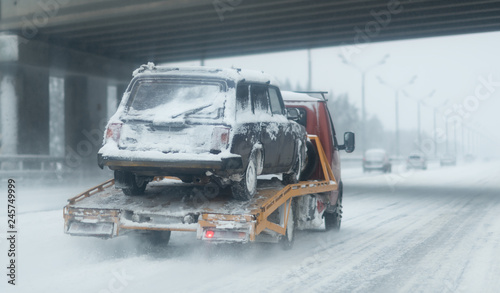 Truck with a car after road accident. Highway with a lot of snow after blizzard