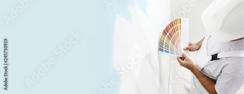 painter man with color swatches in your hand, choice of colors concept, on big blank wall for copy space and web banner background photo